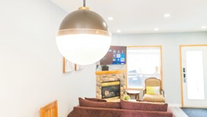 Una sala de estar moderna con una lámpara colgante grande y redonda, una chimenea y un área de descanso confortable.