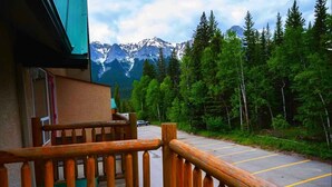 Un balcón de madera con vistas a un estacionamiento y una cordillera boscosa.