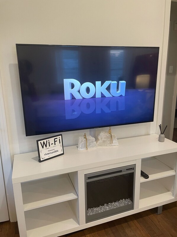 A flat-screen TV on a white entertainment center with a sign indicating Wi-Fi availability and a password.