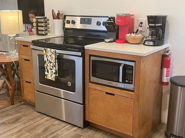 A kitchen with a stainless steel stove, a microwave, and a coffee maker.