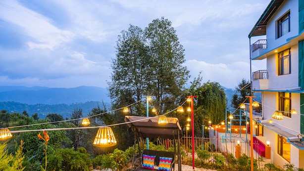 A patio with wicker furniture, a swing, and string lights.