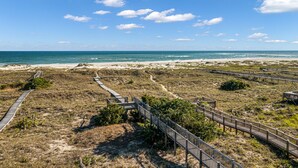 A coastal landscape with a beach, pathways, and wooden boardwalks leading to the water.