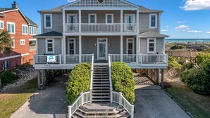 A two-story house with a balcony, a front door, and a staircase leading to the entrance.