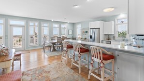 A spacious kitchen with a bar area, large windows, and a view of the outdoors.