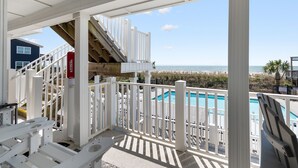 A balcony with a view of a swimming pool and the ocean. - "Waters Edge 429-D" - Oceanfront Condo w/ Community Pool, 2 Bedrooms / 2 Bathrooms (Holden Beach)