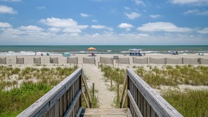 A wooden boardwalk leading to a beach with umbrellas and beach chairs. - "Waters Edge 429-D" - Oceanfront Condo w/ Community Pool, 2 Bedrooms / 2 Bathrooms (Holden Beach)