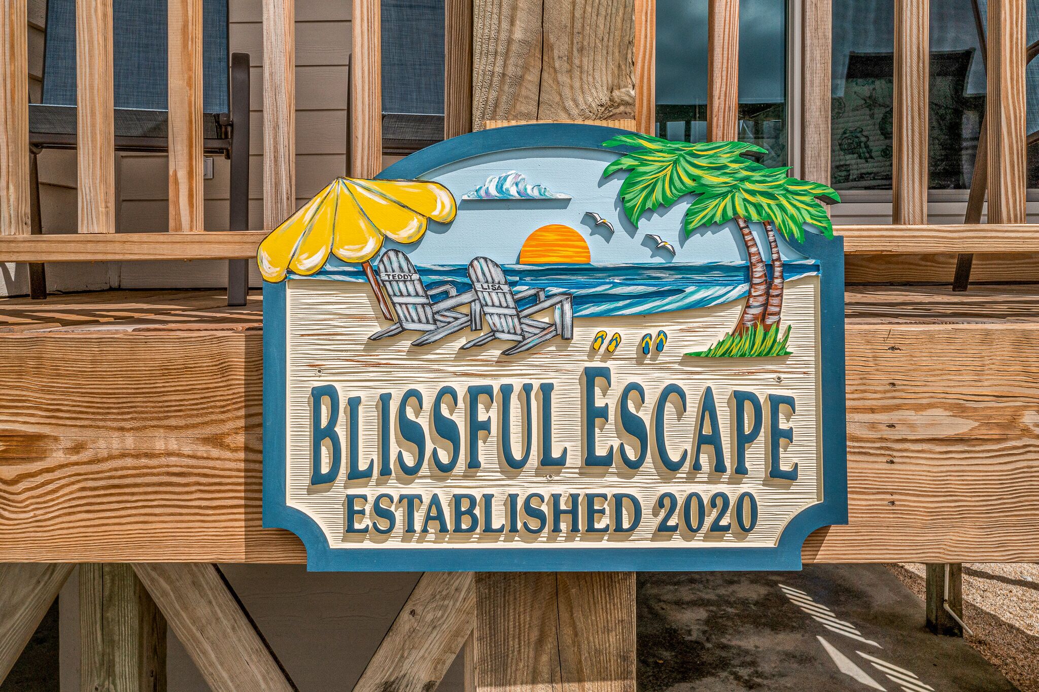 En träskylt med texten ”BLISSFUL ESCAPE – GRUNDAT 2020” och en illustration som föreställer en strand.