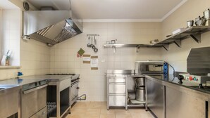 Una cocina comercial con electrodomésticos de acero inoxidable, campana extractora y salpicadero de azulejos.
