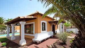 A house with a patio, white columns, and a pool.
