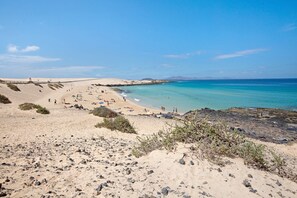 A beach with clear turquoise water, sandy areas, and rocky terrain.