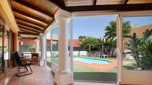A covered patio with a pool, outdoor furniture, and a view of the backyard.