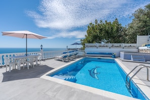 Une piscine décorée avec un motif de dauphin, des chaises longues et une table avec des parasols.