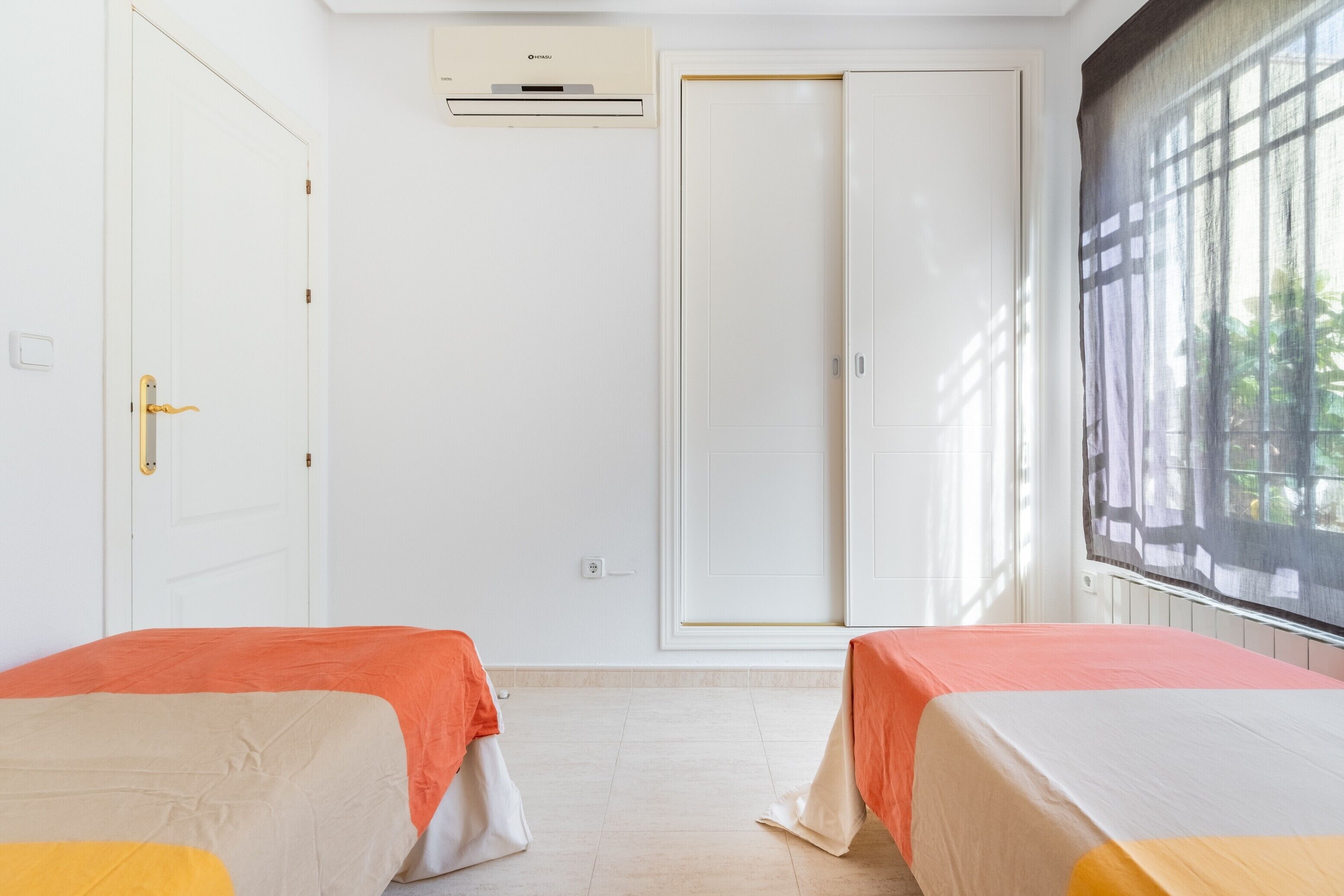 Habitación de hotel con dos camas, un armario, aire acondicionado y ventana con vistas.