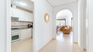 Une cuisine moderne avec des meubles blancs, une cuisinière et une machine à café. On y trouve également un coin repas avec un canapé et une table.