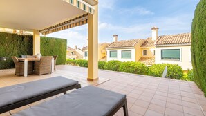 Un espace extérieur abrité comprenant des chaises longues, une table et une pergola.