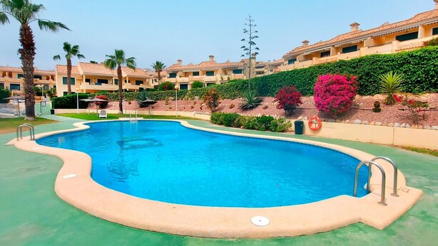 Une piscine à bordures courbes, entourée d’une terrasse verdoyante.