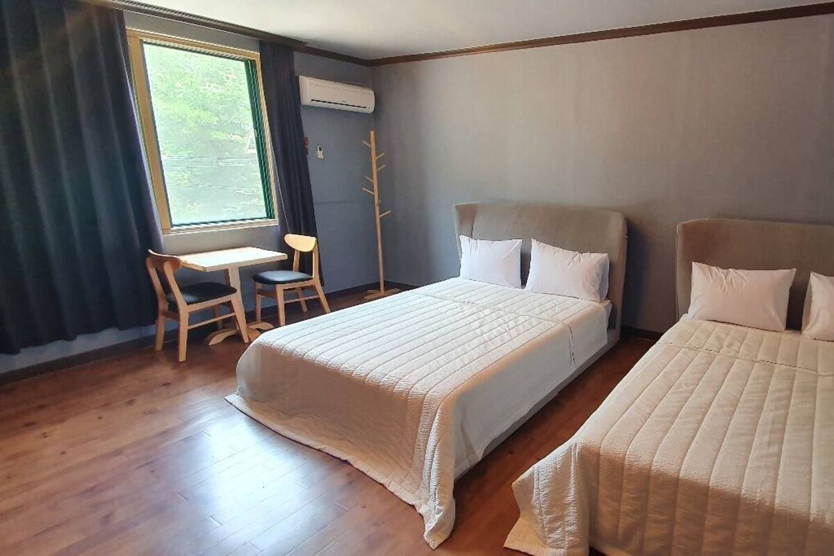 Habitación de hotel con dos camas, un escritorio y una silla.