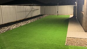A well-maintained artificial green lawn with a metal fence and a stone pathway leading to a building. - STONEHAVEN, perfect holiday accommodation for families. Close to GV Hospital (Shepparton)