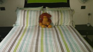 A bed with striped bedding and a plush toy in the center. - Manuela Antonio Comfort ocupado (Quepos)