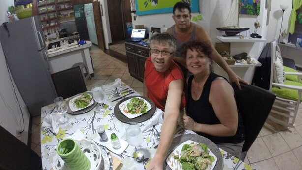 A dining area with a table set for three, a kitchen in the background, and artwork on the walls. - Manuela Antonio Comfort ocupado (Quepos)