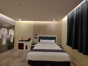 A hotel room with a bed, bedside table, and a small desk with a coffee machine. - Jeju Ilua Hotel (Jeju City)