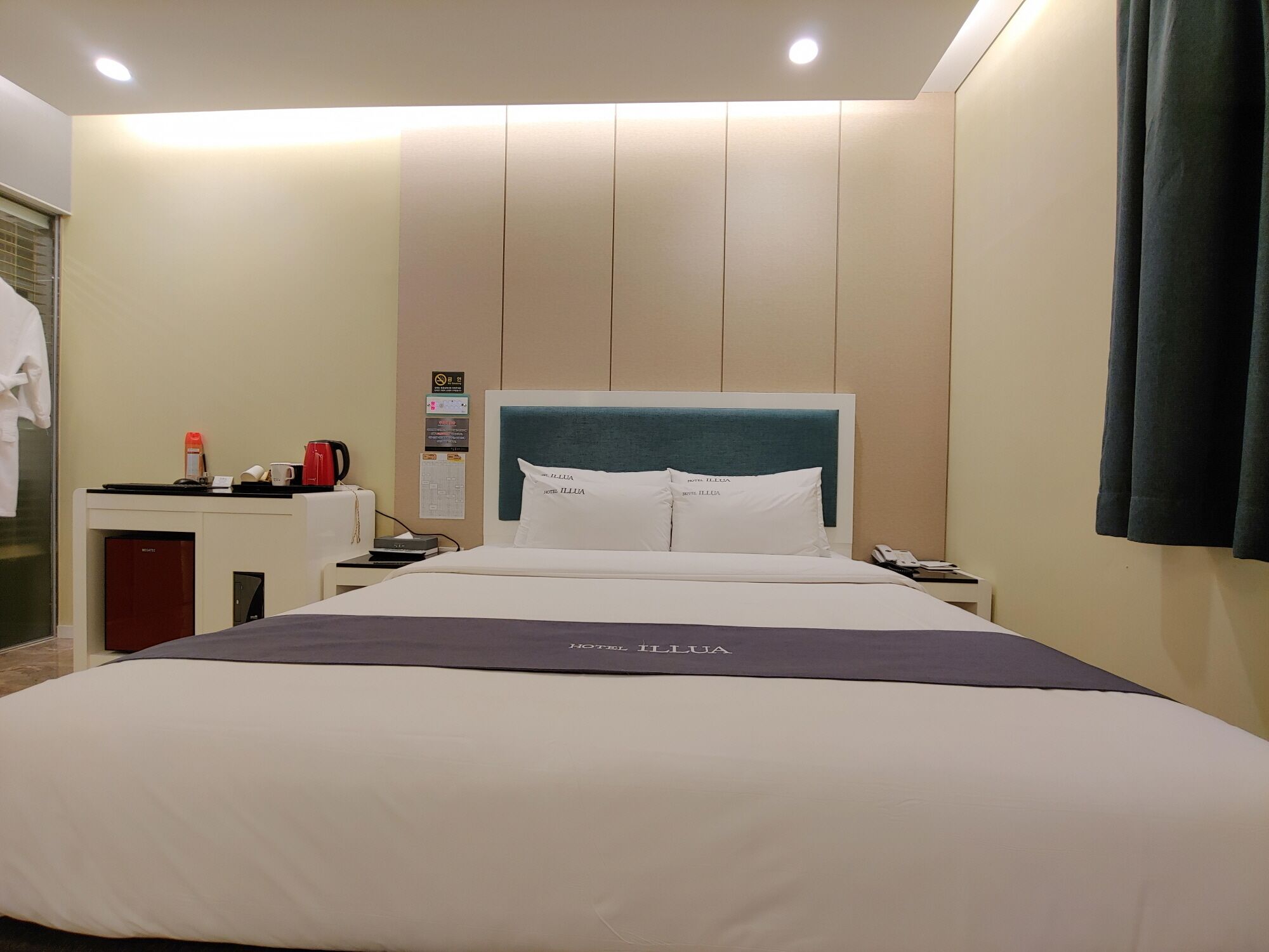 Hotelkamer met een groot bed, een bureau met koffiezetapparaat, een telefoon en een prikbord met verschillende berichten.