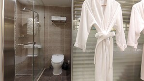A modern bathroom with a glass shower enclosure, a toilet, and a towel rack. - Jeju Ilua Hotel (Jeju City)