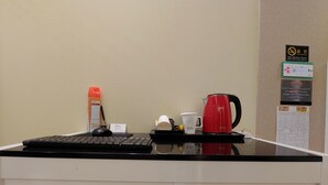 A reception desk with a computer, a red coffee maker, a bottle of hand sanitizer, and a white mug. - Jeju Ilua Hotel (Jeju City)