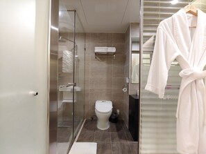 A modern bathroom with a glass shower enclosure, a toilet, and a towel rack. - Jeju Ilua Hotel (Jeju City)