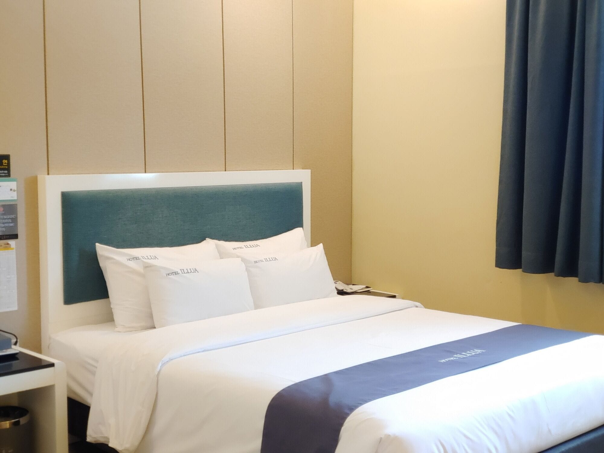 A hotel room with a bed, a nightstand, and a desk.