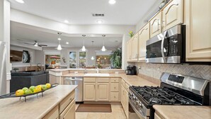 A modern kitchen with a gas stove, stainless steel appliances, and light-colored cabinetry. - Pool & Golf Cart: Sun City Grand Home! (Surprise)