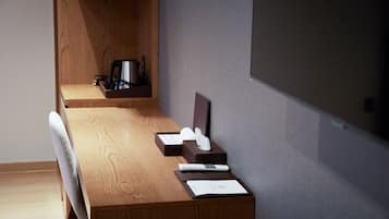 A wooden desk with a tissue box, remote control, and papers.
