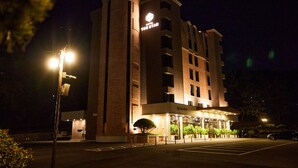 A hotel with a prominent cylindrical tower, a well-lit entrance, and a parking area. - Hotel The Star (Yeonggwang)