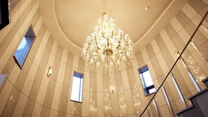 A grand staircase with a chandelier, leading to a high-ceilinged area with patterned walls and small windows. - Hotel The Star (Yeonggwang)
