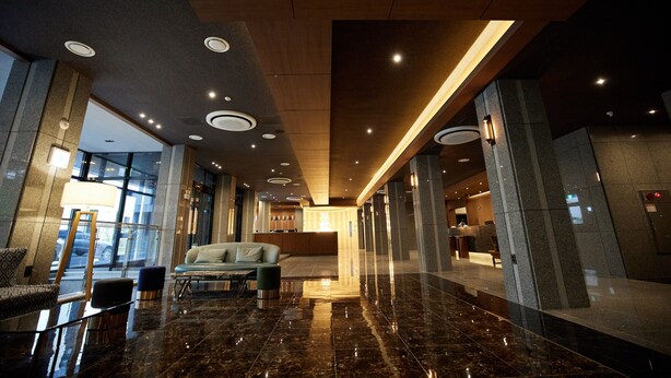 A spacious lobby with a marble floor, a reception desk, and a seating area with a sofa and armchairs. - Hotel The Star (Yeonggwang)