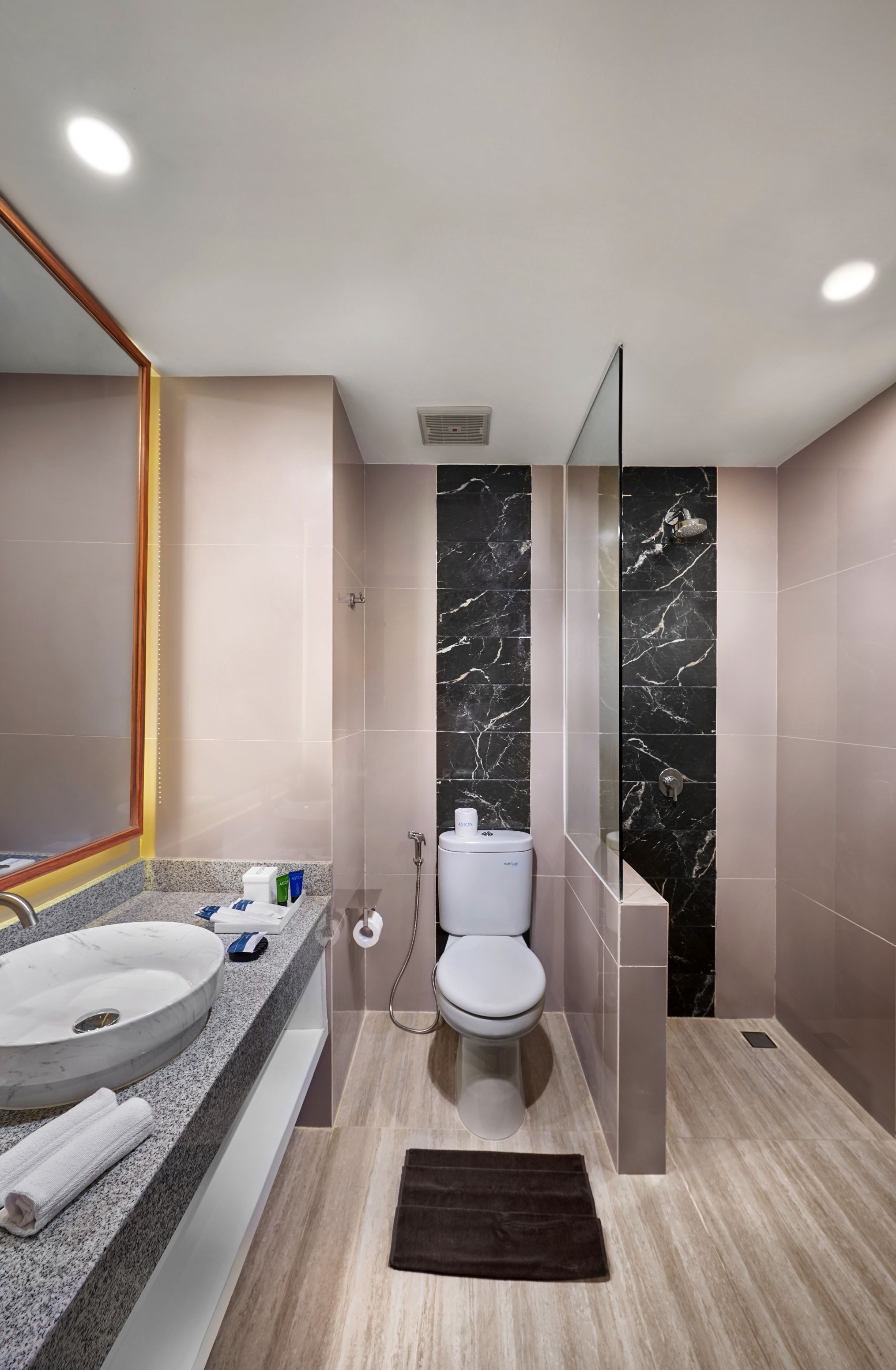 A modern bathroom with a marble backsplash, a round sink, a toilet, and a shower area.
