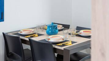 Una mesa de comedor dispuesta con platos, vasos y una tetera azul.