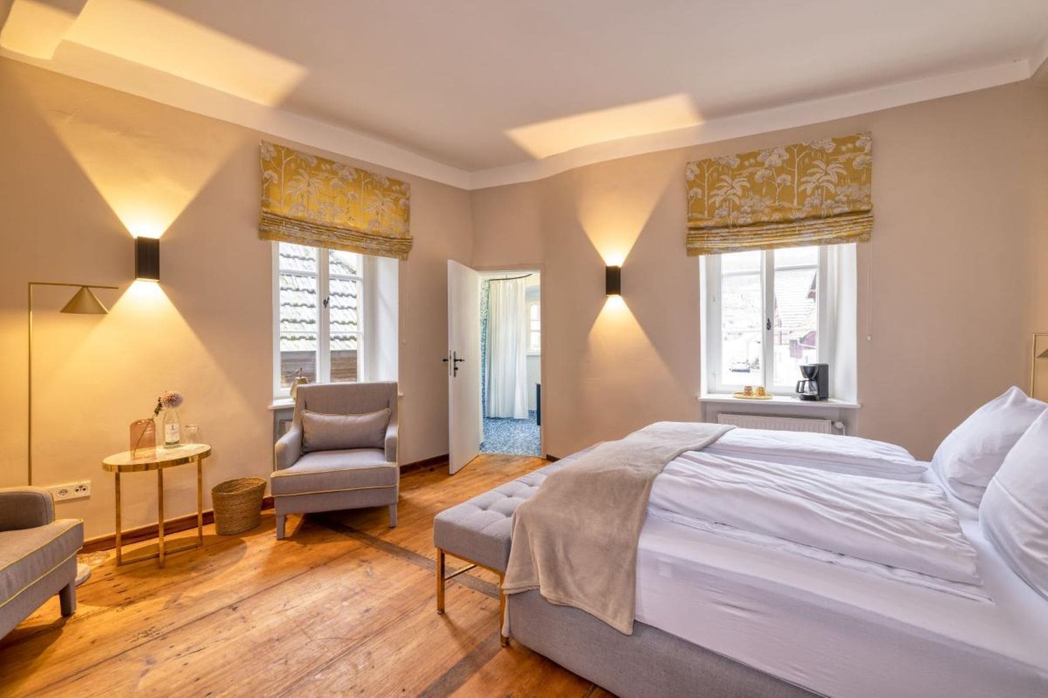 Une chambre à coucher comprenant un lit, une chaise, une petite table et deux lampes fixées au mur.