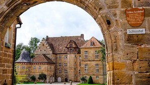 Un edificio histórico con un arco de piedra, un cartel que indica 'Schlosshof' y un estilo arquitectónico europeo tradicional.