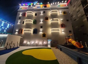 A hotel with a colorful facade, multiple balconies, and a children's play area with a slide. - Almond Kids Hotel (Gimhae)