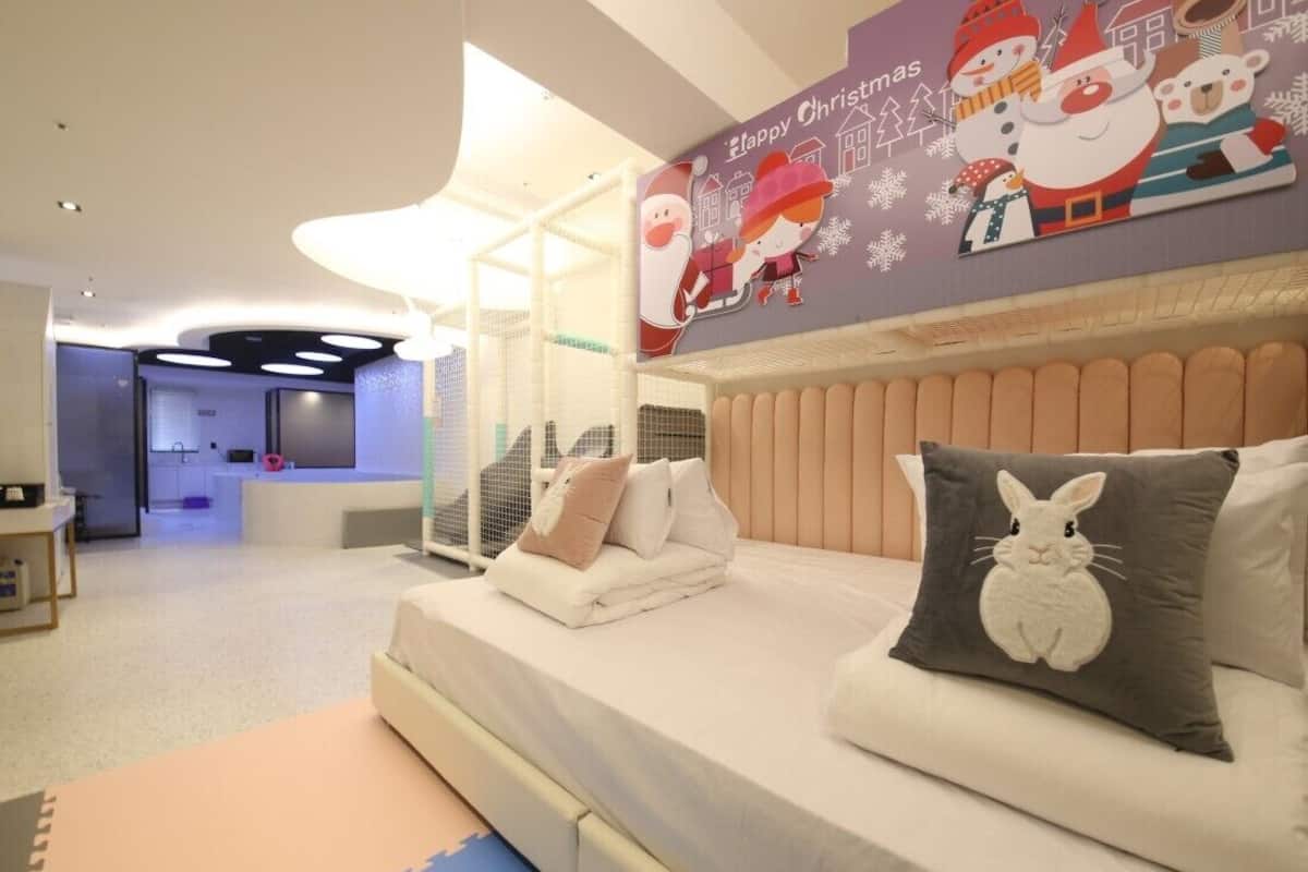 Una habitación de hotel moderna con una cama grande, un cabecero con televisor incorporado y una decoración navideña.
