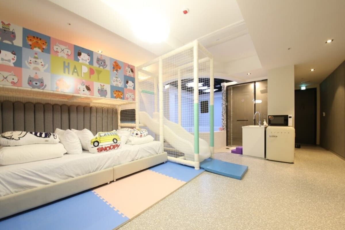 Habitación para niños con cama, zona de juegos y un tobogán.