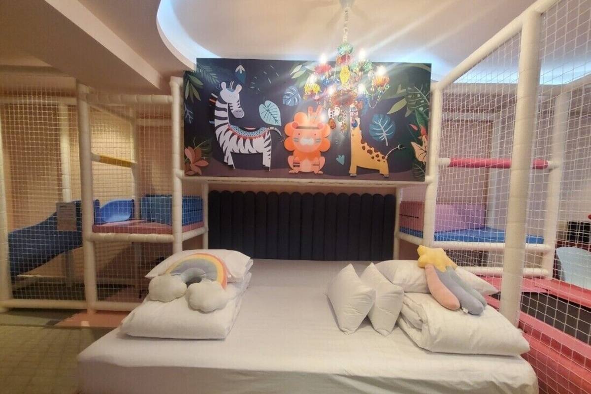 Zona de juegos infantiles con cama, literas y un mural de animales.