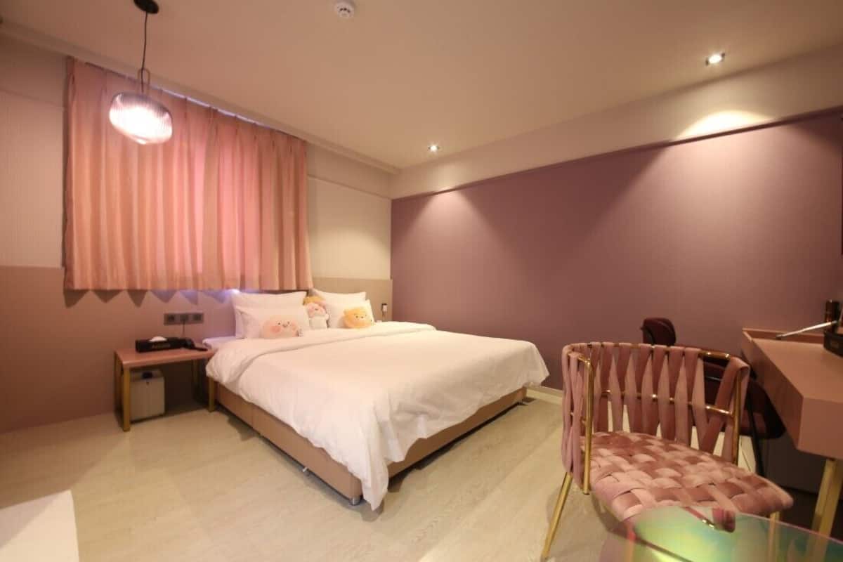 Una habitación de hotel moderna con una cama grande, un escritorio y una silla.