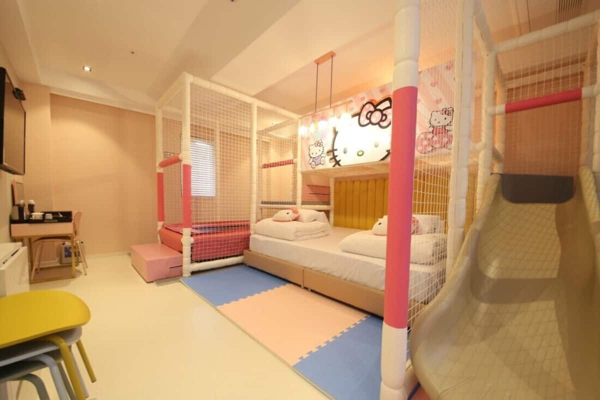 Zona de juegos infantiles con tobogán, estructuras de juego cubiertas con mosquiteras y una cama decorada con motivos de Hello Kitty.