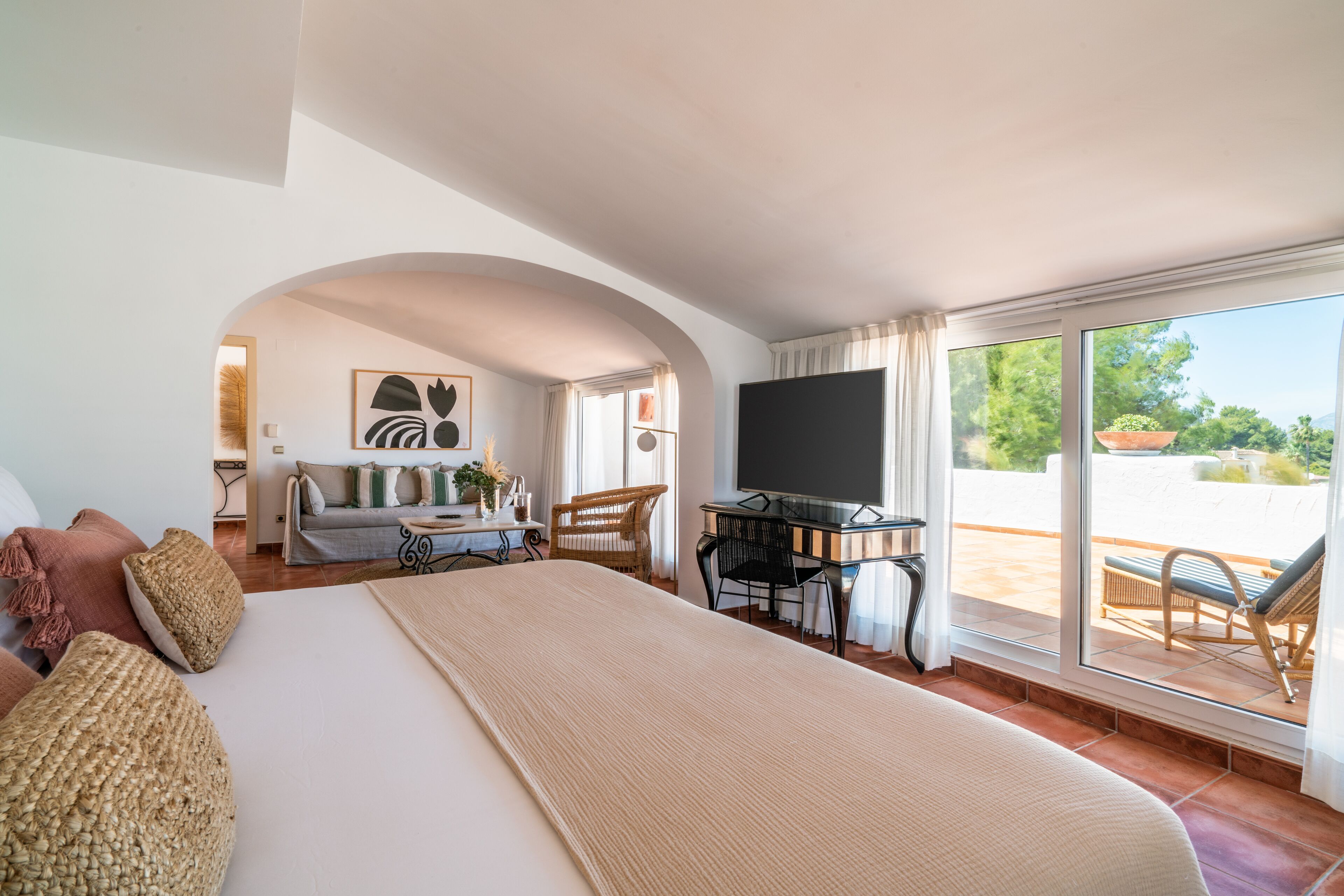 A spacious bedroom with a large bed, a desk, and a view of the outdoors.