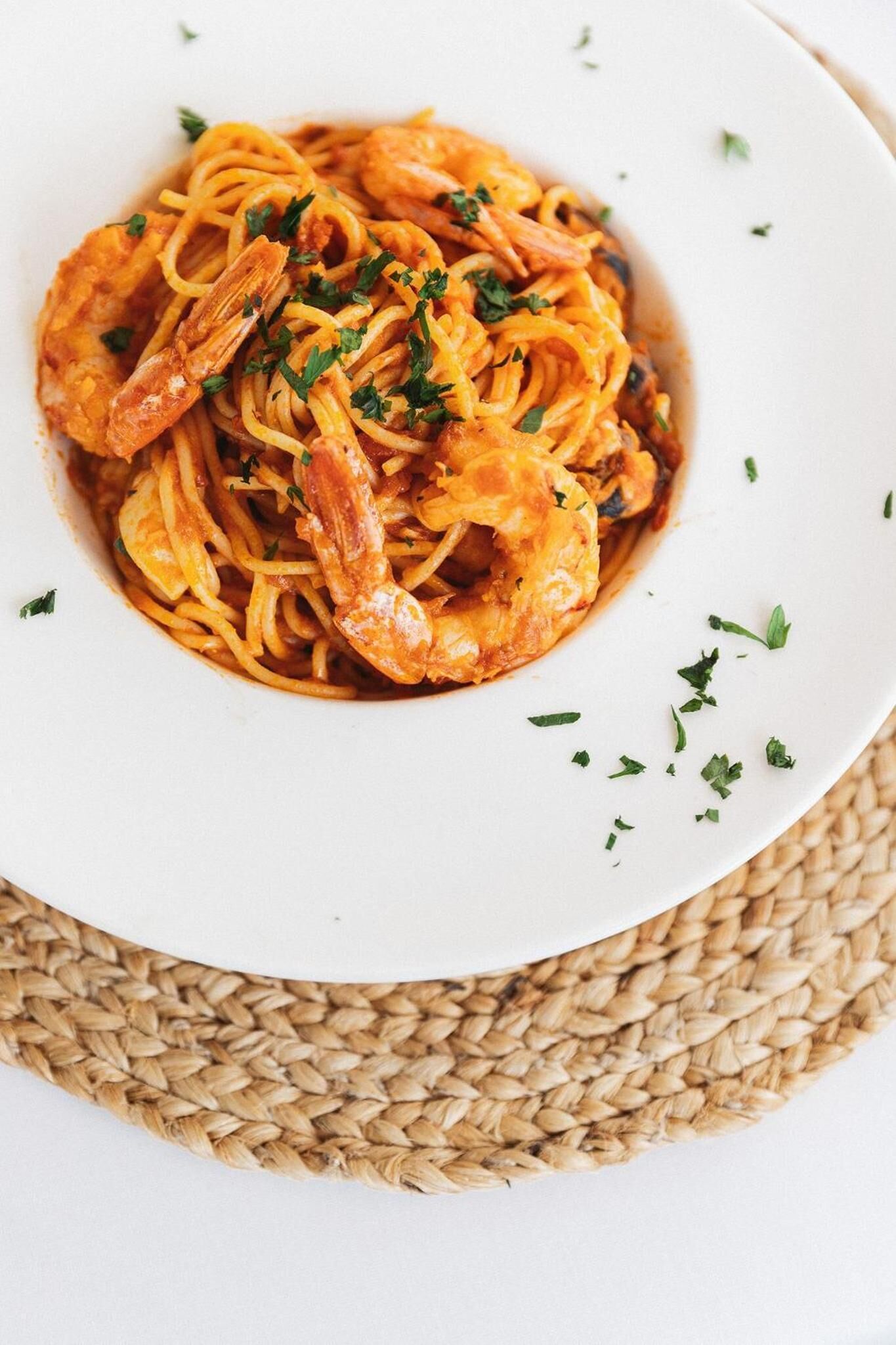A plate of spaghetti with shrimp and parsley garnish.