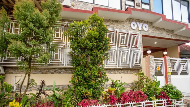 A building with a sign reading "OYO" and a white fence with plants in front. - OYO 805 La Belladoza (Parañaque)