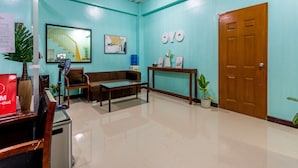 A reception area with a blue wall, a wooden door, a reception desk, a brown sofa, a coffee table, and a water dispenser. - OYO 805 La Belladoza (Parañaque)