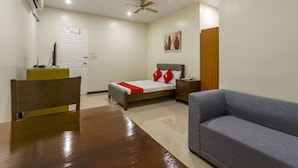 A hotel room with a bed, a desk, a chair, a sofa, a ceiling fan, and a painting on the wall. - OYO 805 La Belladoza (Parañaque)
